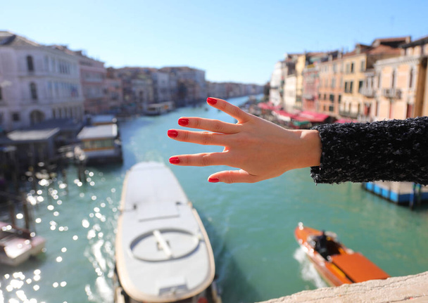 Cinco dedos de la mano de la joven con uñas con esmalte de uñas rojo y el Gran Canal en Venecia ITALIA - Foto, Imagen