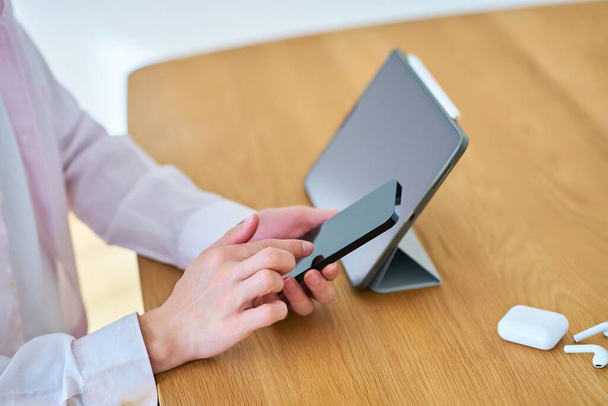 Руки человека, управляющего планшетным компьютером и смартфоном в комнате - Фото, изображение