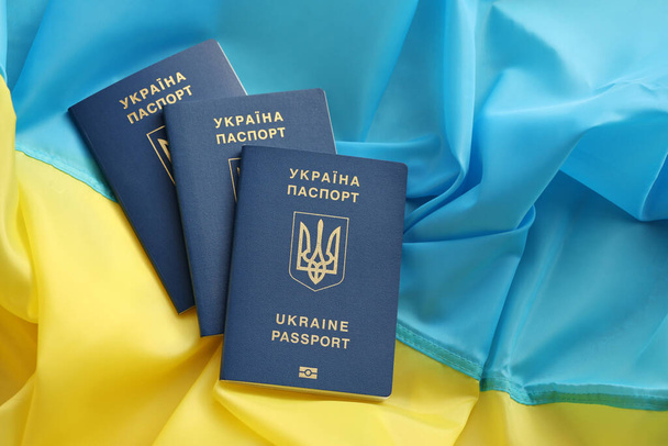 Trzy ukraińskie paszporty biometryczne na składanej fladze kraju Ukraina zbliżyć - Zdjęcie, obraz