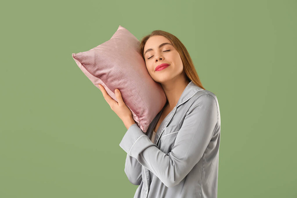 Piękna młoda kobieta z różową miękką poduszką na zielonym tle - Zdjęcie, obraz