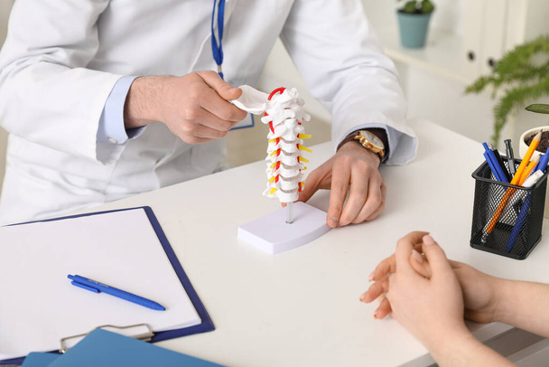 Médico masculino explicando a anatomia espinhal com modelo de coluna vertebral para paciente na clínica, close-up - Foto, Imagem