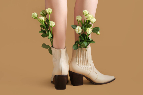 Bej arkaplanda beyaz güller olan bej çizmeli güzel genç bayanların bacakları. Arka plan - Fotoğraf, Görsel