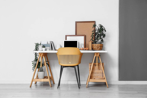 Интерьер офиса с удобным рабочим местом, стулом, комнатными растениями и современным ноутбуком - Фото, изображение