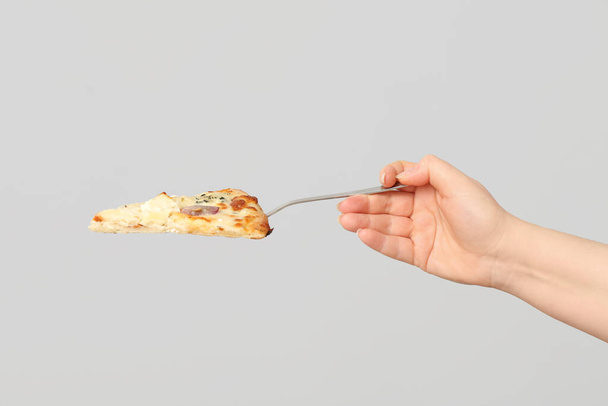 Mão feminina segurando saborosa fatia de pizza com espátula no fundo branco - Foto, Imagem