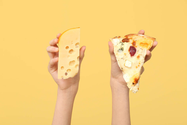 Female hands holding pizza slice and cheese on yellow background - Photo, Image