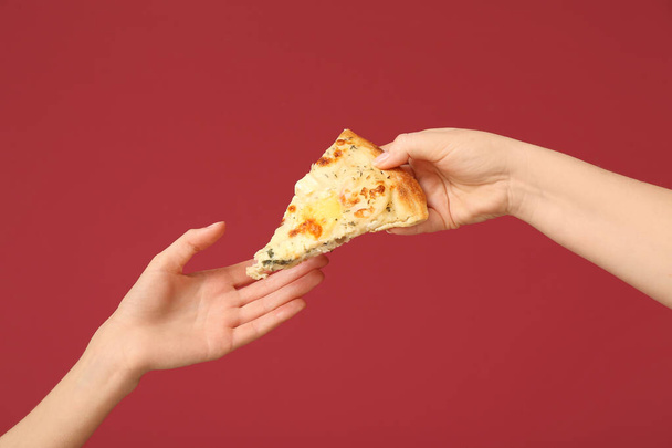 Female hand giving tasty pizza slice on red background - Photo, Image