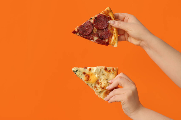 Naisten kädet tilalla maukkaita pizza viipaleita oranssi tausta - Valokuva, kuva