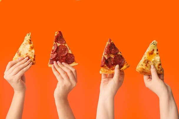 Many hands holding tasty pizza slices on orange background - Photo, Image