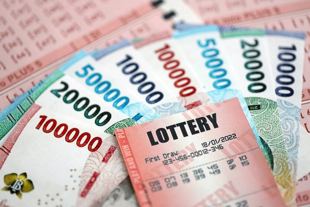 Червоний лотерейний квиток лежить на рожевих азартних іграх з індонезійськими рупійними грошима. Лотерея грає концепцію або залежність від азартних ігор в Індонезії - Фото, зображення