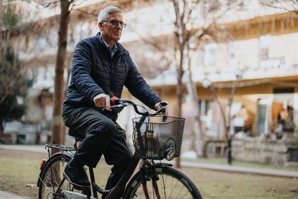 Un gentleman âgé faisant du vélo tranquillement dans un parc paisible, représentant un mode de vie actif et sain pour les aînés. - Photo, image