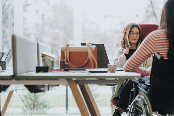 Ambiente aziendale inclusivo con giovane donna sulla sedia a rotelle alla riunione dell'ufficio. - Foto, immagini