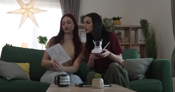 dos mujeres hermanas o amigos compañeros de piso en casa conectar e instalar la cámara de vigilancia cctv - Metraje, vídeo