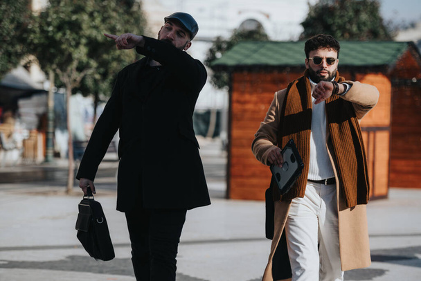 Los hombres jóvenes a la moda al aire libre, con un gesto direcciones a la otra. El atuendo de invierno y el estilo moderno en un entorno urbano evocan un ambiente de moda. - Foto, imagen