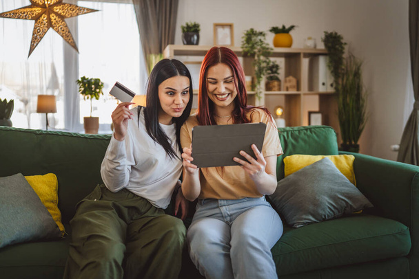 2人の若い女性の姉妹や友人は家に座って,デジタルタブレットでオンラインショッピングブラウズインターネットストアのクレジットデビットカードを購入割引販売実際の人々はスペースをコピーします - 写真・画像