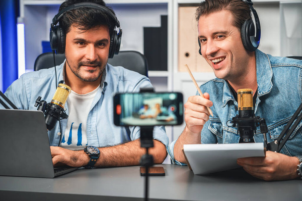 Host channel of creative broadcaster living by smartphone in positive podcast with special guest in list script to advice listeners, wearing headsets, using mic radio record at studio. Sellable. - Foto, Bild