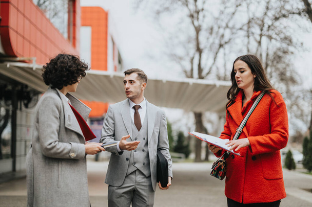 Tre soci d'affari professionisti impegnati in una conversazione seria al di fuori di un ambiente di ufficio urbano. - Foto, immagini