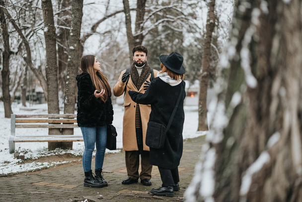Młodzież współpracuje przy projekcie biznesowym w zaśnieżonym parku, prezentując pracę zespołową i odporność w warunkach zimowych. - Zdjęcie, obraz