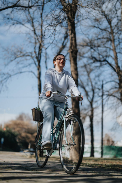 公園のヴィンテージ自転車で晴れた日を楽しんでいる楽しい若い女性. - 写真・画像