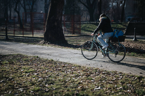 Ciclista casual paseando en bicicleta por un tranquilo parque en un día soleado. - Foto, Imagen