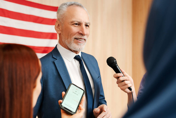Portrait confident senior man, politician, presidential candidate talking with journalists, press, answering questions. 2024 Presidential election concept  - Photo, Image