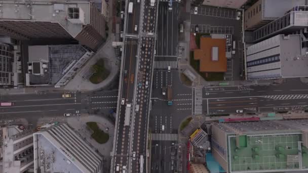 Top down beelden van het verkeer op meerbaans verkeer in de stad. Hoofdweg omgeven door hoge gebouwen. Osaka, Japan. - Video