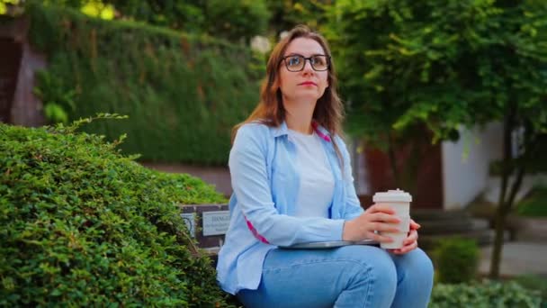 Porträt einer Frau mit Brille hält Kaffee to go in Händen, Zeitlupe. Orbitalschuss - Filmmaterial, Video
