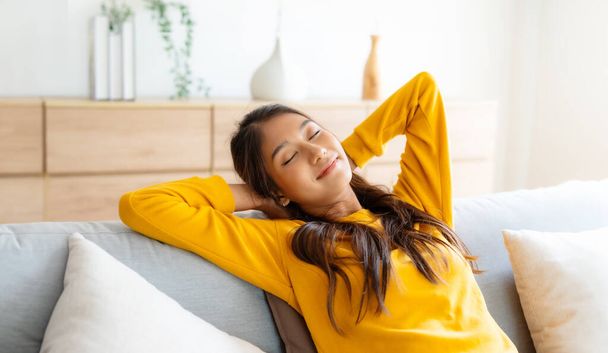 Happy Asian woman relaxing on the sofa at home - Smiling adorable girl enjoying day off lying on the couch, Healthy life style concept - Photo, Image