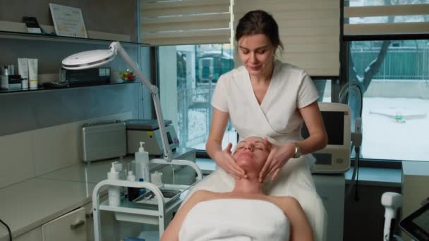 美容師は,診療所の患者にフェイスマッサージを施しています. 高齢の女性のための美のプロシージャをきつく締める皮. 高品質の4k映像 - 映像、動画