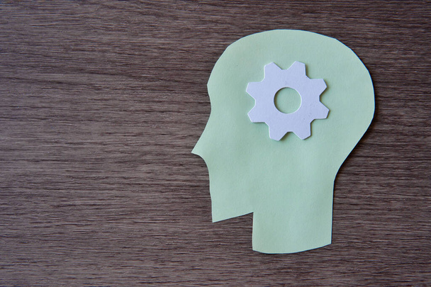Um papel verde recortado de uma cabeça humana com uma engrenagem branca no centro da cabeça. Copiar espaço para texto. Brainstorm, conceito de pensamento. - Foto, Imagem