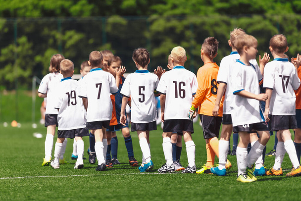 Los jugadores de fútbol de los niños se agradecen mutuamente por jugar después de que termina la competición. Los niños juegan deportes en un campo de hierba. Fútbol niños juego limpio comportamiento después del partido - Foto, imagen
