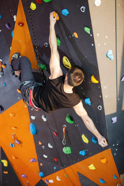 Young man practicing rock-climbing in climbing gym - Photo, Image