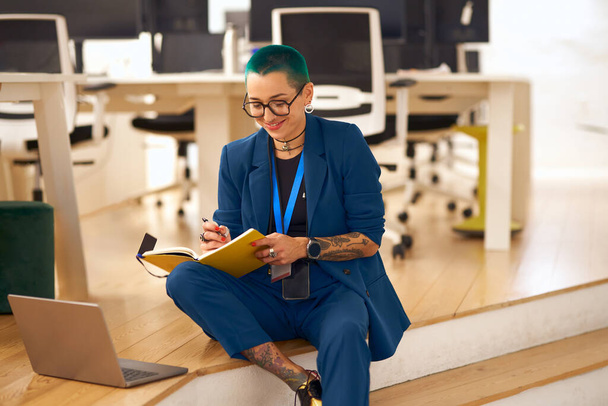 Muito tatuado proprietário do negócio feminino é usar laptop sentado no fundo de co-trabalho moderno - Foto, Imagem