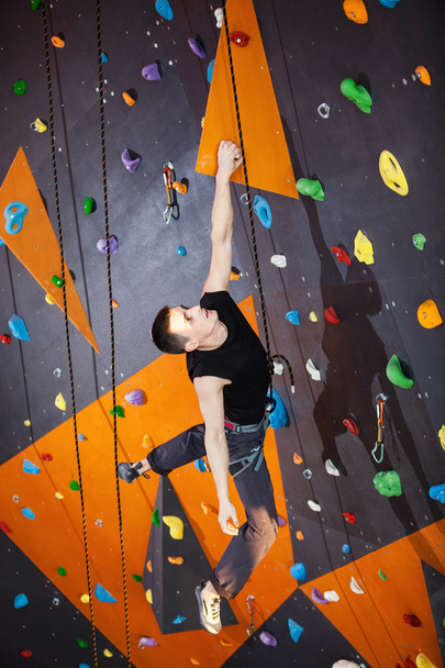 Young man practicing rock-climbing in climbing gym - Photo, Image