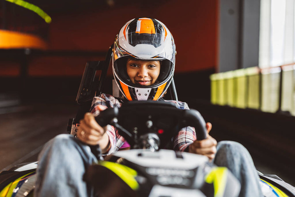 Go-Kartレーサーはヘルメットで運転するアフリカの女性を運転します - 写真・画像