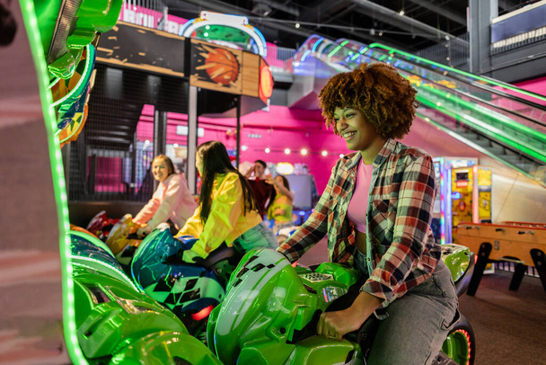 gruppo di amici generazione z, moto ad alta velocità. videogioco su una moto. nella sala ricreativa - Foto, immagini