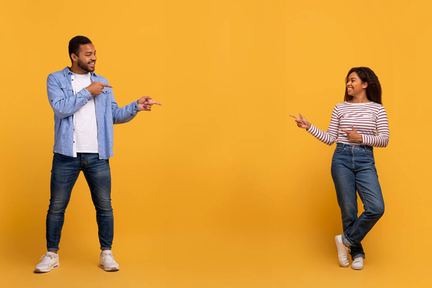 Ezt figyeld! Boldog fekete pár mutat másolás tér közepén a sárga háttér, afro-amerikai férfi és nő ajánló valamit, megmutatva szabad hely a design vagy a reklám - Fotó, kép