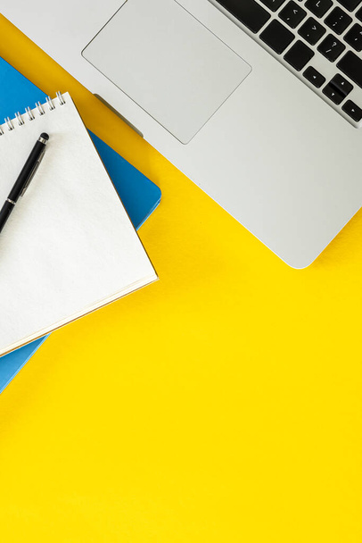 Laptop and notepads on a yellow background, flat lay. Minimal office background, copy space. - Photo, Image