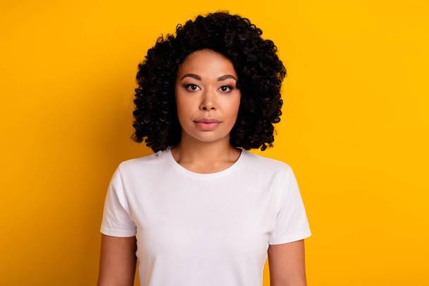 Photo of serious confident woman with perming coiffure dressed white t-shirt look at you isolated on vibrant yellow color background. - Zdjęcie, obraz