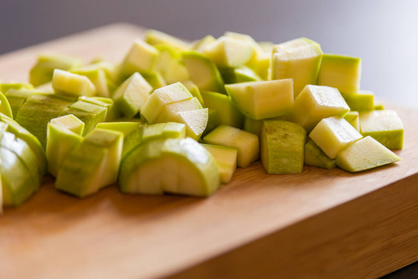 chopped zucchini into cubes on wooden board close-up - Photo, Image