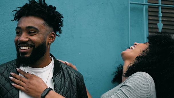 Fröhliches afroamerikanisches Paar teilt das Lachen in der Stadt, glückliche junge Schwarze genießen einen Moment draußen, authentisches Lachen und Lächeln im wirklichen Leben - Foto, Bild