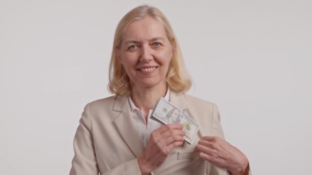 Een succesvolle whitecollar werknemer in een blazer en jurk shirt glimlacht terwijl het houden van geld, het maken van een hart gebaar met haar handen om geluk en welvaart te tonen - Video