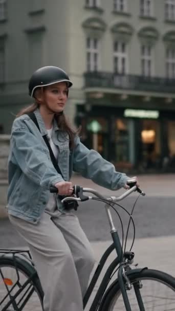 Ευτυχισμένη όμορφη νεαρή γυναίκα ιππασία ποδήλατο στο δρόμο εξωτερική κοντά στην πόλη κτίριο. Χαμογελαστός γυναικείος τρόπος ζωής με ποδήλατο σε καλοκαιρινά ταξιδιωτικά μέσα μεταφοράς, φιλικό προς το περιβάλλον - Πλάνα, βίντεο