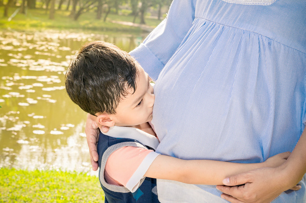Asiático menino beijando a barriga de sua mãe grávida
 - Foto, Imagem