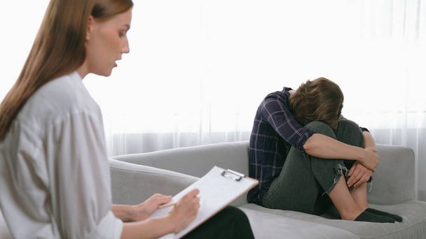 Θλιβερό PTSD γυναίκα ασθενής σε θεραπεία για ψυχική υγεία με ψυχολόγο, κατάθλιψη ή θλίψη μετά την αποτυχία της ζωής. Απογοητευμένο τραύμα νεαρή γυναίκα μιλάει σε prim ψυχολόγο για το συναίσθημα στην κλινική - Φωτογραφία, εικόνα