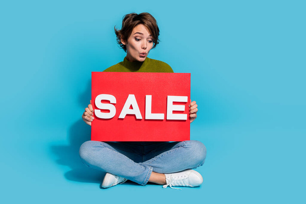 Photo of sweet cute lovey girl sitting floor showing banner low price price sale empty space isolated on cyan color background. - Φωτογραφία, εικόνα