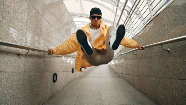 Wykwalifikowany azjatycki hipster spacerujący w wąskim korytarzu. Blisko break tancerki ćwiczącej break dance. Profesjonalista przechodzi do muzyki. Sport na świeżym powietrzu 2024. Sprytnie. - Zdjęcie, obraz