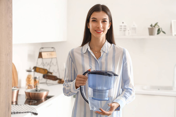 Молодая женщина с кувшином для фильтра воды на кухне - Фото, изображение