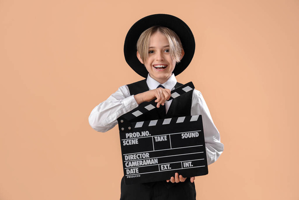 Little actor with movie clapper on beige background - Foto, Bild