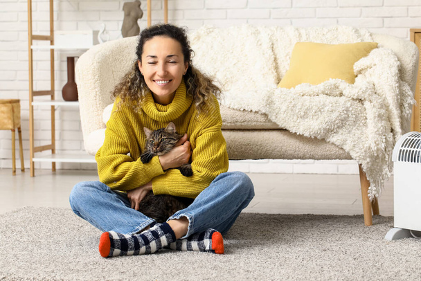 Ευτυχισμένη ώριμη γυναίκα με χαριτωμένο γάτα κάθεται στο πάτωμα στο σπίτι - Φωτογραφία, εικόνα