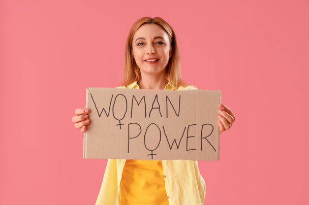 Mature lady holding paper with text WOMAN POWER on pink background - Photo, Image